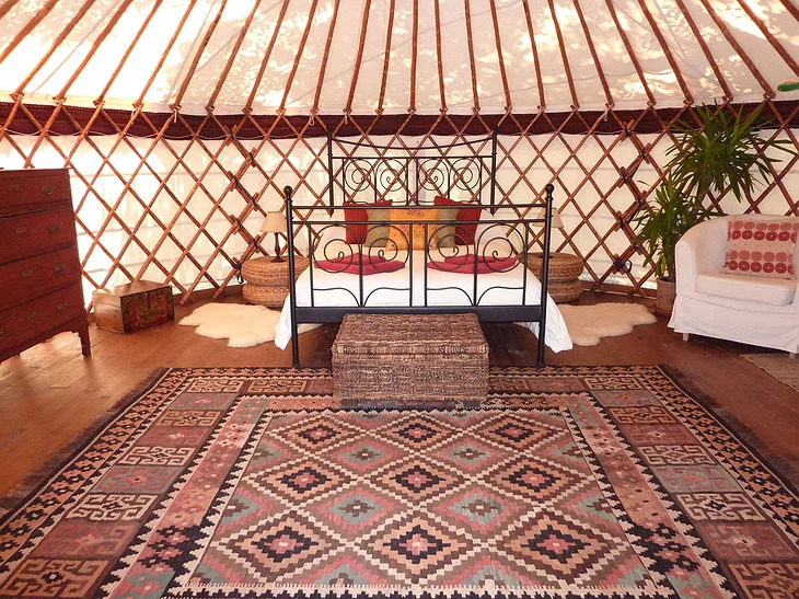 Interior of a canvas Yurt Workshop yurt with exposed chestnut frame and roof poles