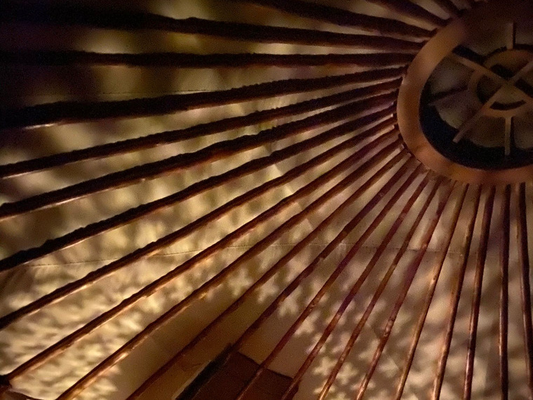 Chestnut roof poles and oak crown inside a Yurt Workshop yurt at night