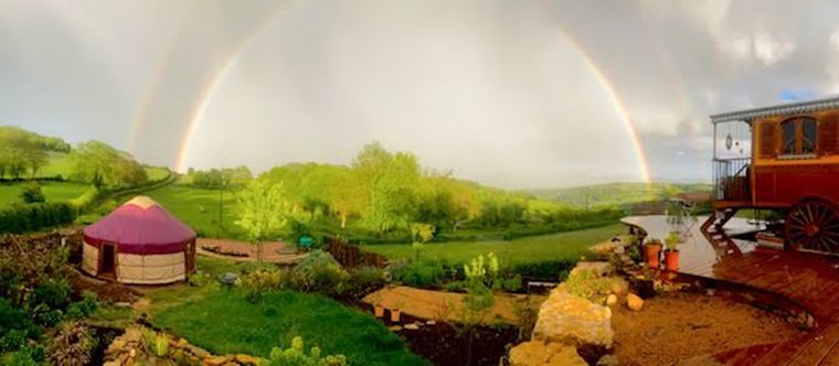 Coloured insulated Yurt Workshop yurt with wooden door and separate window beneath a rainbow