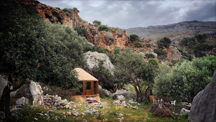 Glass Wall yurt set among rocks and olive trees in a mountain landscape