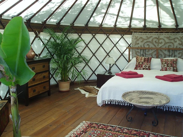 Bright interior of a Yurt Workshop yurt showing the natural chestnut lattice and roof poles