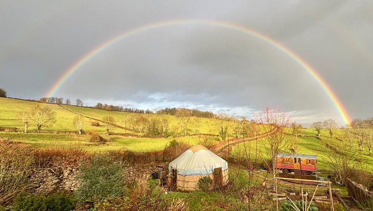 Insulated Yurt Workshop yurt beneath a rainbow in a rural landscape