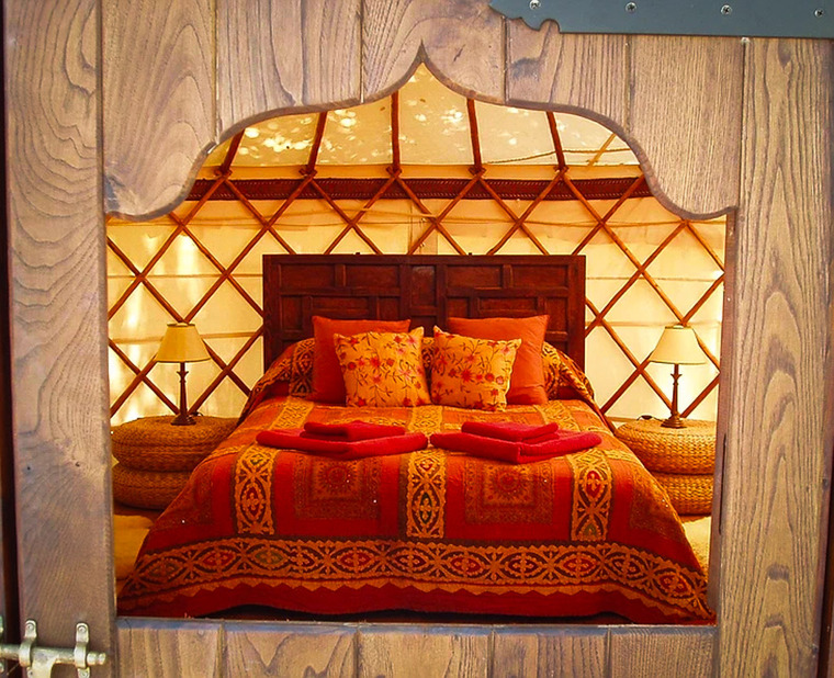 Warm interior of a Yurt Workshop yurt, viewed through the wooden doorway